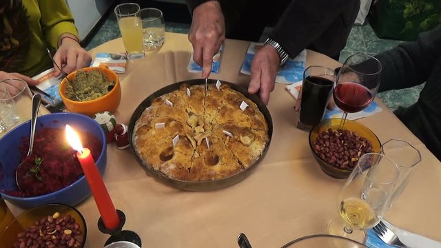 Family around Christmas Eve dinner table. The grandfather breaks the bread with fortunes traditional way of celebrating the Christmas Eve. Candle lit on the table gives warmth and romance feeling.