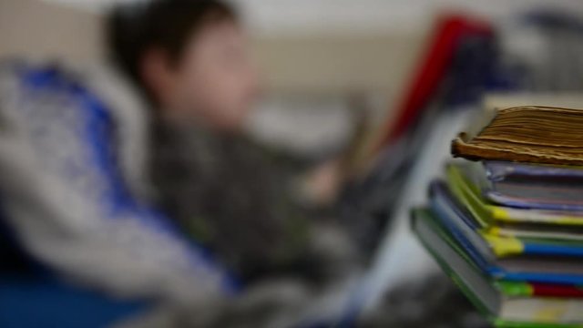 little boy reading book in bed 