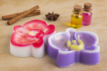 Original handmade soap shaped like orchid. Essential oil, cinnamon and anise on the background.