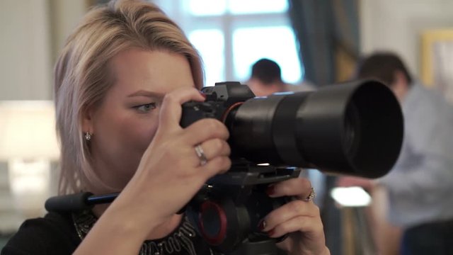 Young woman working with mirrorless camera on monopod indoors