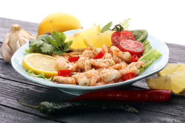fresh shrimps served on a plate with garlic onion, lemon and chili
