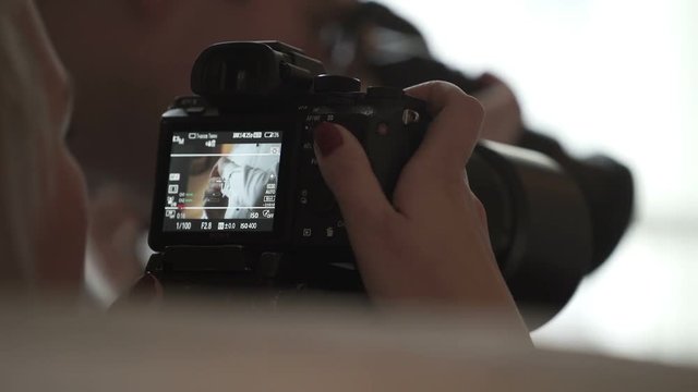 Young woman working with camera shooting man wearing cufflinks indoors