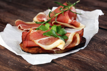 Bread with slices jamon serrano for lunch table. Sharing antipasti on party or summer picnic time...