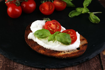 Bread with cream cheese and tomato for lunch table. Sharing antipasti on party or summer picnic time over wooden rustic background.