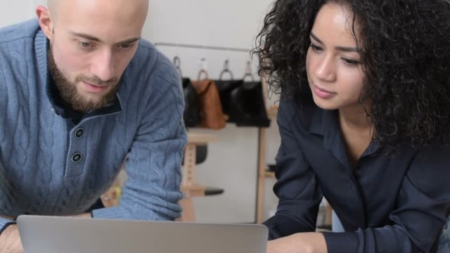 Owners of a small fashion design studio reading email on laptop