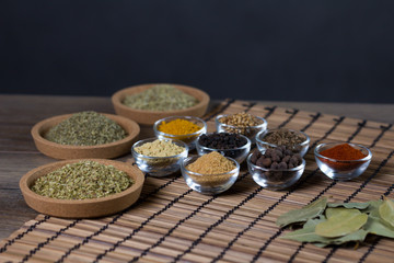 Various spices in bowls with fresh seasoning on rustic wooden background, closeup