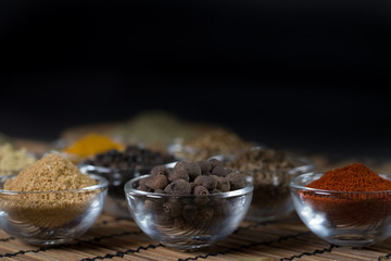Various spices in bowls with fresh seasoning on rustic wooden background, closeup