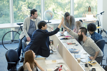 Colleagues high-fiving in casual office