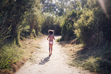 Rear view of a little girl walking on dirt road