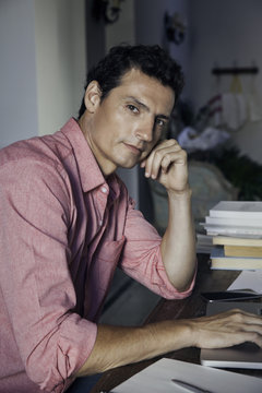 Man pausing in thought while using laptop computer, portrait