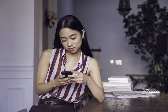 Woman text messaging with smartphone