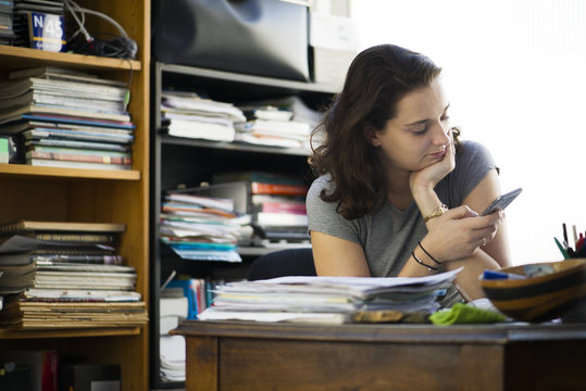 Office worker taking break to browse social media using smartphone