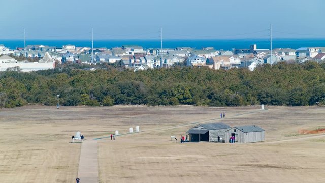 Wright Brothers National Memorial Park Airfield View of the Historical First Flight Location Alongside Wooden Hangars and Living Quarter Sheds with Buildings and the Atlantic Ocean in the Background