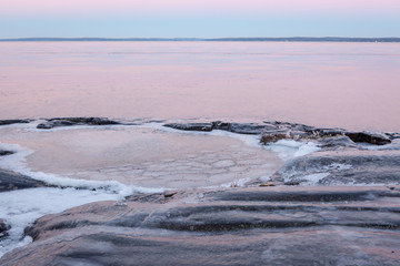 Frozen rock lake shore at dusk
