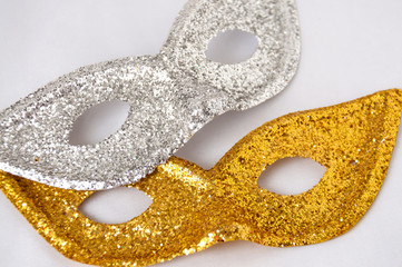 Gold and silver theatrical masks on a light background