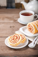 Swiss roll with jam and tea on a table. Selective focus. Copy space.