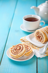 Swiss roll with jam and tea on a table. Selective focus. Copy space.