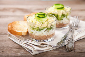 Layer tuna, cucumber and egg salad in a glass on a table. Selective focus. Copy space