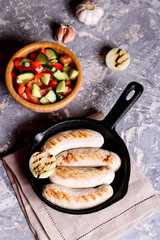 Sausages in rustic pan with onion. Top view. Frying pan with fried sausage and vegetables
