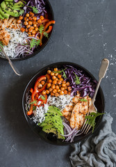 Grilled chicken, rice, spicy chickpeas, avocado, cabbage, pepper buddha bowl on dark background, top view. Delicious balanced food concept