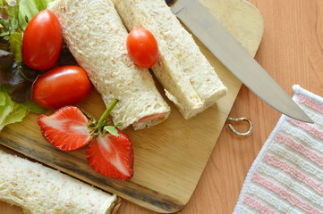bread roll and salad on wooden chop plate