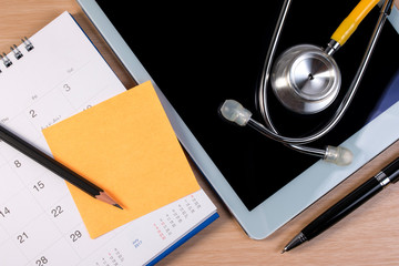 Close up of stethoscope book and pen on calendar, doctor appointment. Booking reminder plan for health checkup.