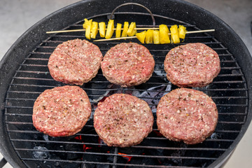 Grilled meat on a charcoal griddle accompanied by onions in foil and pineapple.