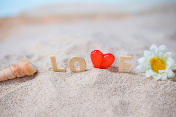 Obraz na płótnie Canvas valentine decoration with love wooden text and beach chair on white sand beach with tropical blue sea and clear blue sky,Image For Love Valentine Day or summer vacation Concept.