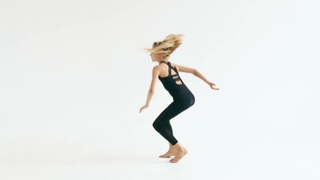 Slow motion of beautiful teenage girl dancer dancing contemporary on white background indoors