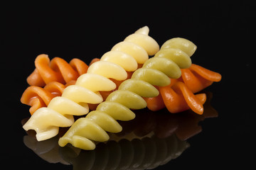 Colored spiral pasta isolated on black background