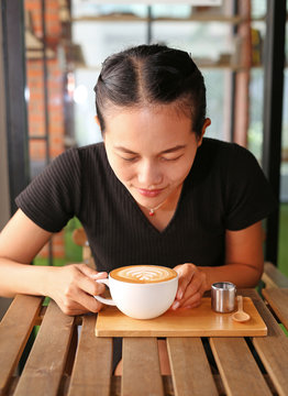 Woman drinking hot coffee in the morning, with heart shape pattern on coffee cup.