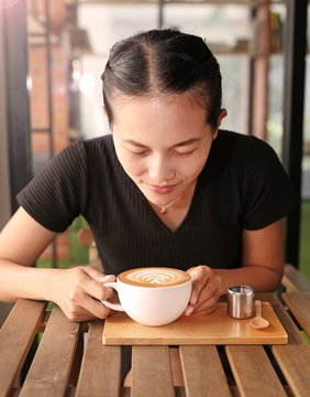 Woman drinking hot coffee in the morning, with heart shape pattern on coffee cup.
