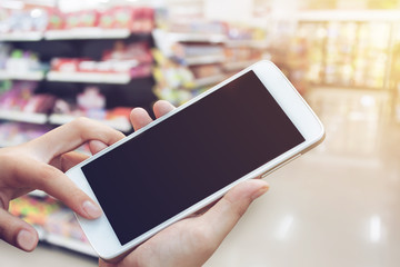 woman hand hold and touch screen smartphone, tablet,cellphone over blurred shopping center or super market background.