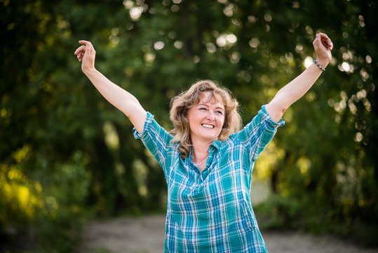 Carefree dancing mature woman against nature background