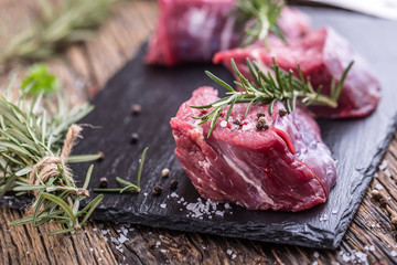 Raw beef meat. Raw beef tenderloin steak on a cutting board with rosemary pepper salt in other positions.