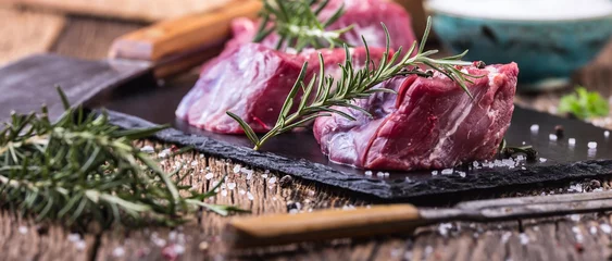 Foto auf Acrylglas Fleish Raw beef meat. Raw beef tenderloin steak on a cutting board with rosemary pepper salt in other positions.