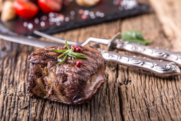 Grilled beef steak with rosemary, salt and pepper on old cutting board. Beef tenderloin steak.