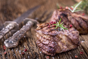 Grilled beef steak with rosemary, salt and pepper on old cutting board. Beef tenderloin steak.