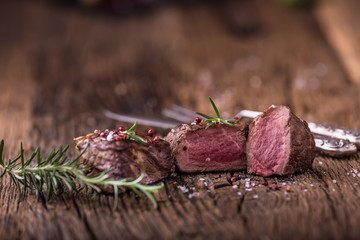 Grilled beef steak with rosemary, salt and pepper on old cutting board. Beef tenderloin steak.