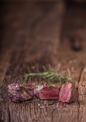 Grilled beef steak with rosemary, salt and pepper on old cutting board. Beef tenderloin steak.
