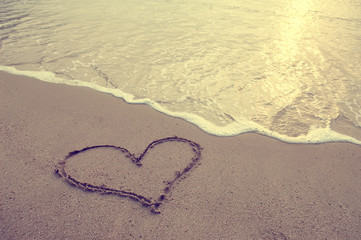 Obraz na płótnie Canvas heart drawn in the sand on the beach. Romantic design element.