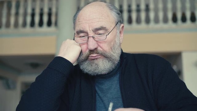 Emotional tired old man sitting, smoking cigarette thinking, scratching head 4K