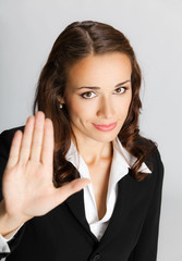  Businesswoman with stop gesture, over grey