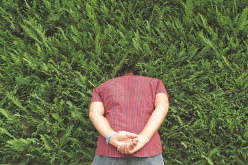 Guy hiding his head in the bushes.