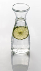 Bottle with water and slice of lime isolated on white background