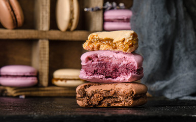 Three colorful bite macaroons on black table. French delicious dessert clouseup