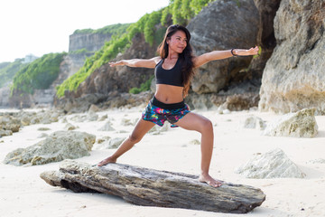 Young adult girl doing yoga at the beach 