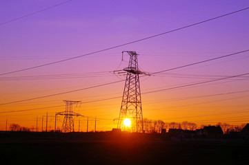 High voltage distribution power lines pylon at sunset