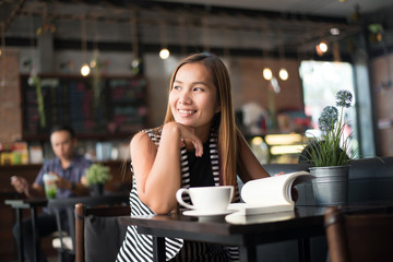 Asian woman relaxing and reading a book in the cafe. Women lifestyle concept.