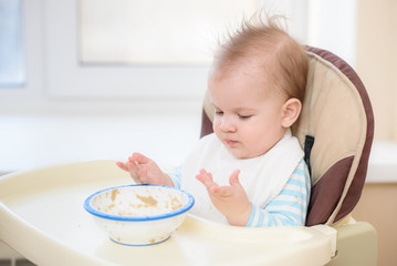 Kid eats porridge hands of the plate
